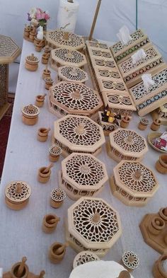 a table topped with lots of wooden vases and bowls on top of a white table cloth