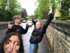 two people standing next to each other with their fingers in the air and one person holding up his peace sign