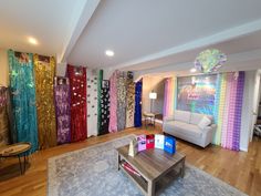 a living room filled with furniture and lots of colorful curtains on the wall behind it