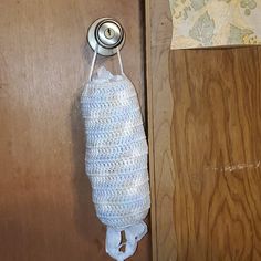 a crocheted bag hanging from a hook on a wooden door with a map in the background