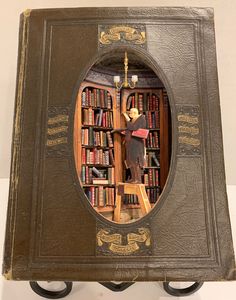 an old book with a miniature figurine in the middle and bookshelves behind it