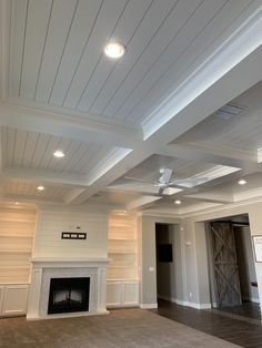 an empty living room with a fireplace and ceiling fan