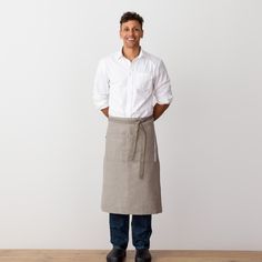 a man standing in front of a white wall wearing an apron