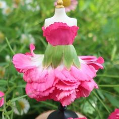 a pink flower with a white mannequin on top