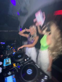 two women dancing in front of dj's at a party