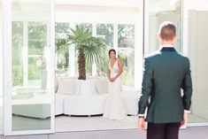 a man and woman standing in front of a white couch looking at each other,