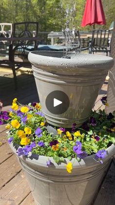 a potted planter filled with flowers on top of a wooden deck