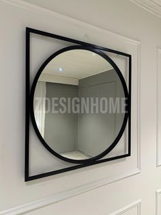 a round mirror hanging on the wall above a doorway with white walls and black trim