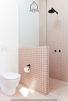 a white toilet sitting in a bathroom next to a walk in shower and tiled walls