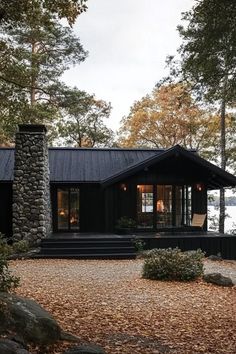 a black cabin is surrounded by trees and rocks