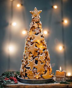 a christmas tree made out of cookies on a tray next to a lit candle and some lights