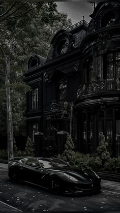 a black sports car parked in front of a large victorian style house on a dark street