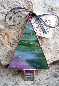 a glass christmas tree ornament sitting on top of a rock