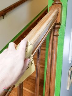 a hand is holding a piece of paper on the bannister rail that has been painted green