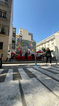 people are walking down the street in front of a building with graffiti painted on it