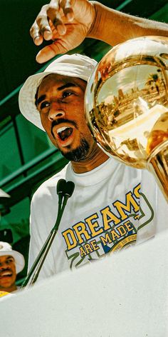 a man wearing a white hat and holding up a trophy in front of his face