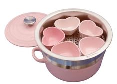 a pink pot filled with lots of heart shaped dishes next to a spoon and lid