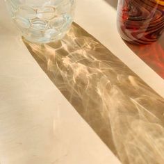 two vases sitting on top of a table next to each other with water in them