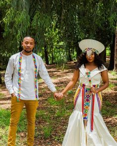 a man and woman dressed in african clothing holding hands while standing next to each other