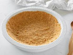 a white bowl filled with brown sugar next to a wooden spoon on a marble counter