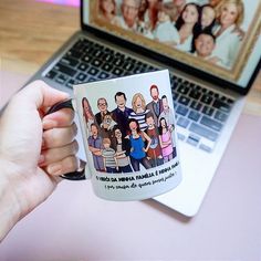 a person holding a coffee mug in front of a laptop computer with a family photo on it