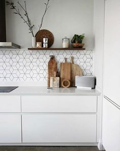 a kitchen with white cabinets and shelves filled with cooking utensils, cutting boards and plants