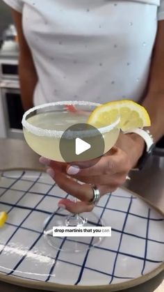 a woman holding a martini glass with lemon wedges