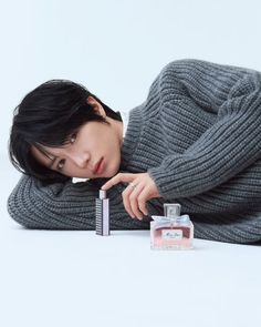 a woman laying on the ground next to a bottle of perfume