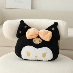 a black and white cat pillow with a bow on it's head sitting on a chair