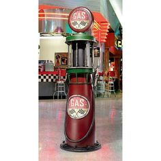 a red and green gas pump sitting in the middle of a floor next to a restaurant