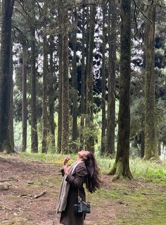 a woman standing in the middle of a forest