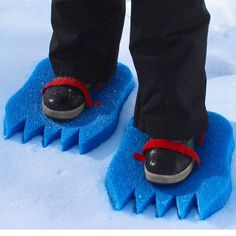 the feet of a person standing on a blue snowboard with red straps and black shoes