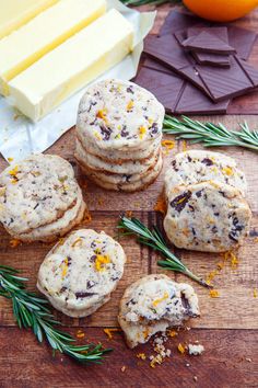 cookies with orange zest and chocolate chips on a wooden cutting board next to cheese