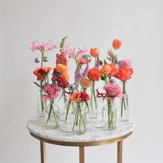 several vases filled with different colored flowers on a marble table