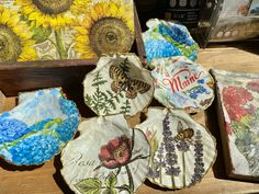 four plates with flowers and butterflies painted on them sitting on a table next to a wooden box