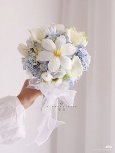 a bride holding a bouquet of white and blue flowers