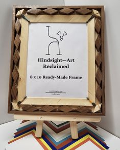 a wooden frame sitting on top of a pile of multicolored papers next to a sign that says hindsight - art reclaimed