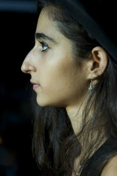 a close up of a person wearing a hat and looking off into the distance with her eyes closed