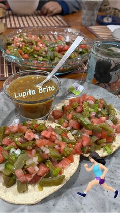 two pita breads filled with vegetables and salsa on top of a table next to bowls of dip