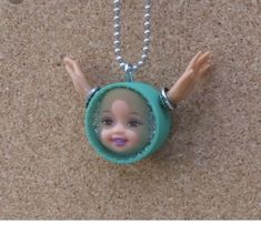 a necklace with a doll's head in the center and hands hanging from it