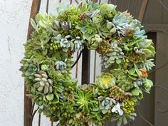 a wreath with succulents is hanging on a fence