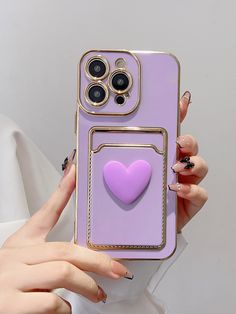 a woman holding up a phone case with a heart on it