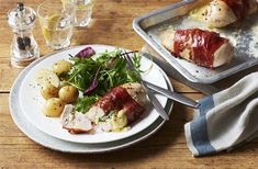 two plates with meat and vegetables on them sitting on a table next to silverware