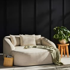 a living room with black walls and a round couch next to a potted plant