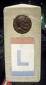 a stone block with a coin on it and a red ribbon around the edge that says l