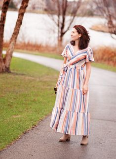 a woman in a striped dress is walking down the street