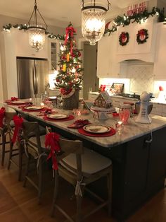 a christmas tree in the middle of a kitchen island with plates and place settings on it