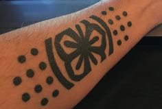 a person with a tattoo on their arm that has dots and a flower in the center