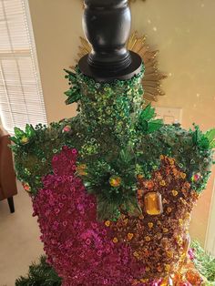 the top of a mannequin made out of flowers and plants is covered in fake leaves