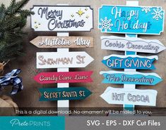 several wooden signs hanging on a wall next to a christmas tree with presents in it